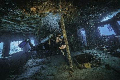 scuba diver exploring inside a military shipwreck