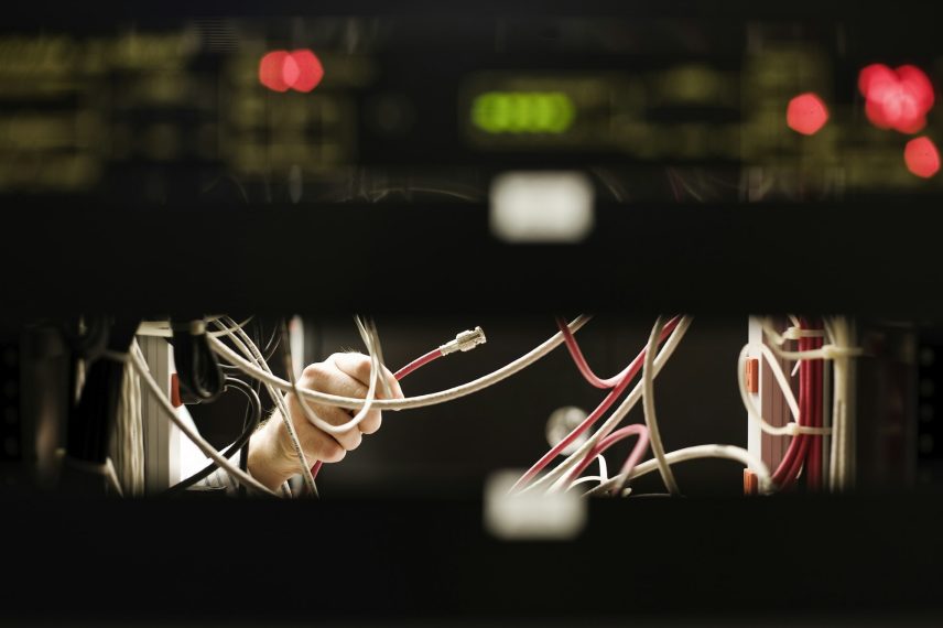 Technician working on main racks of servers in a computer server room.